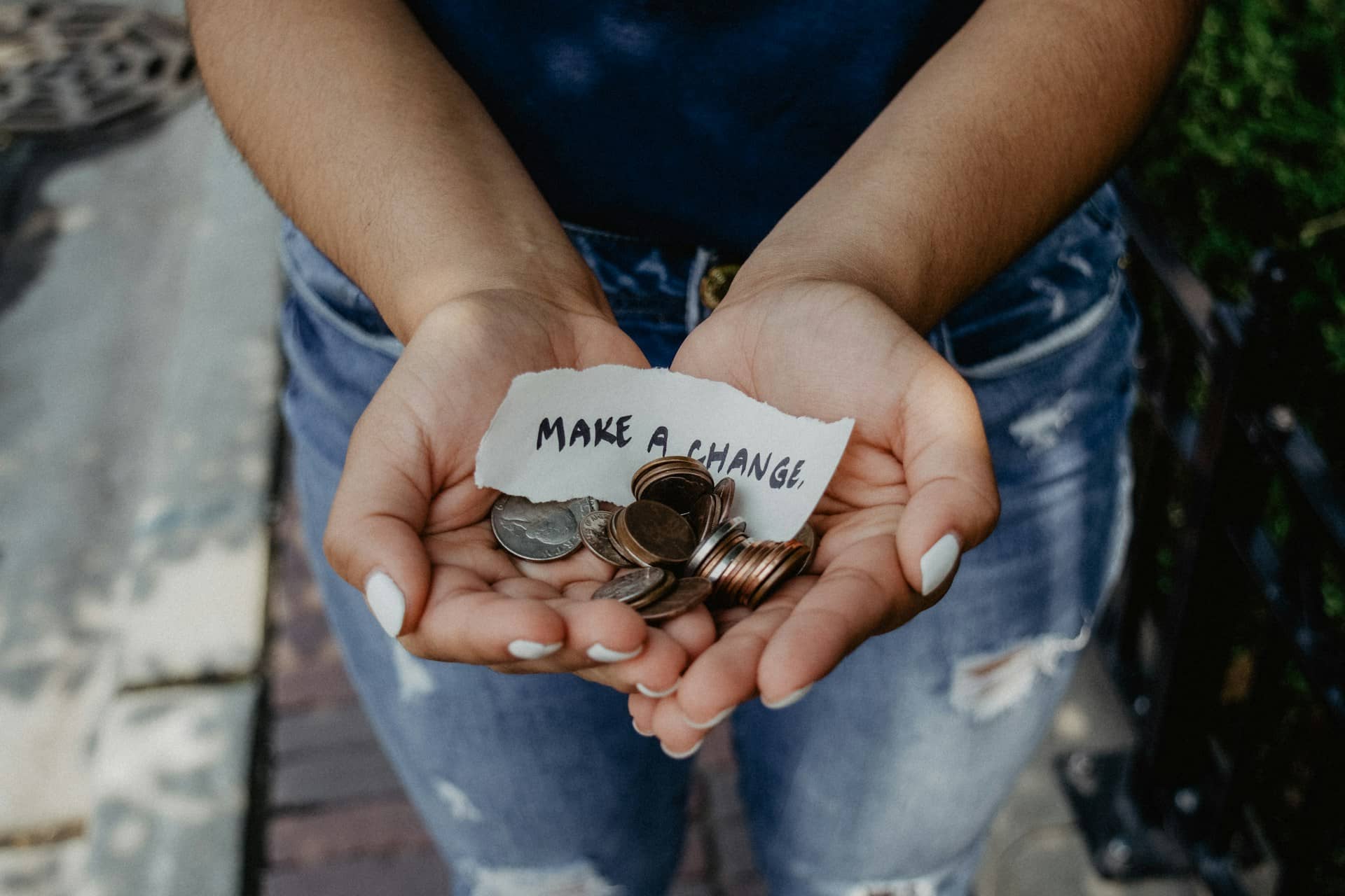 Girl holding a note saying 'Make a Change; in her hands and some money